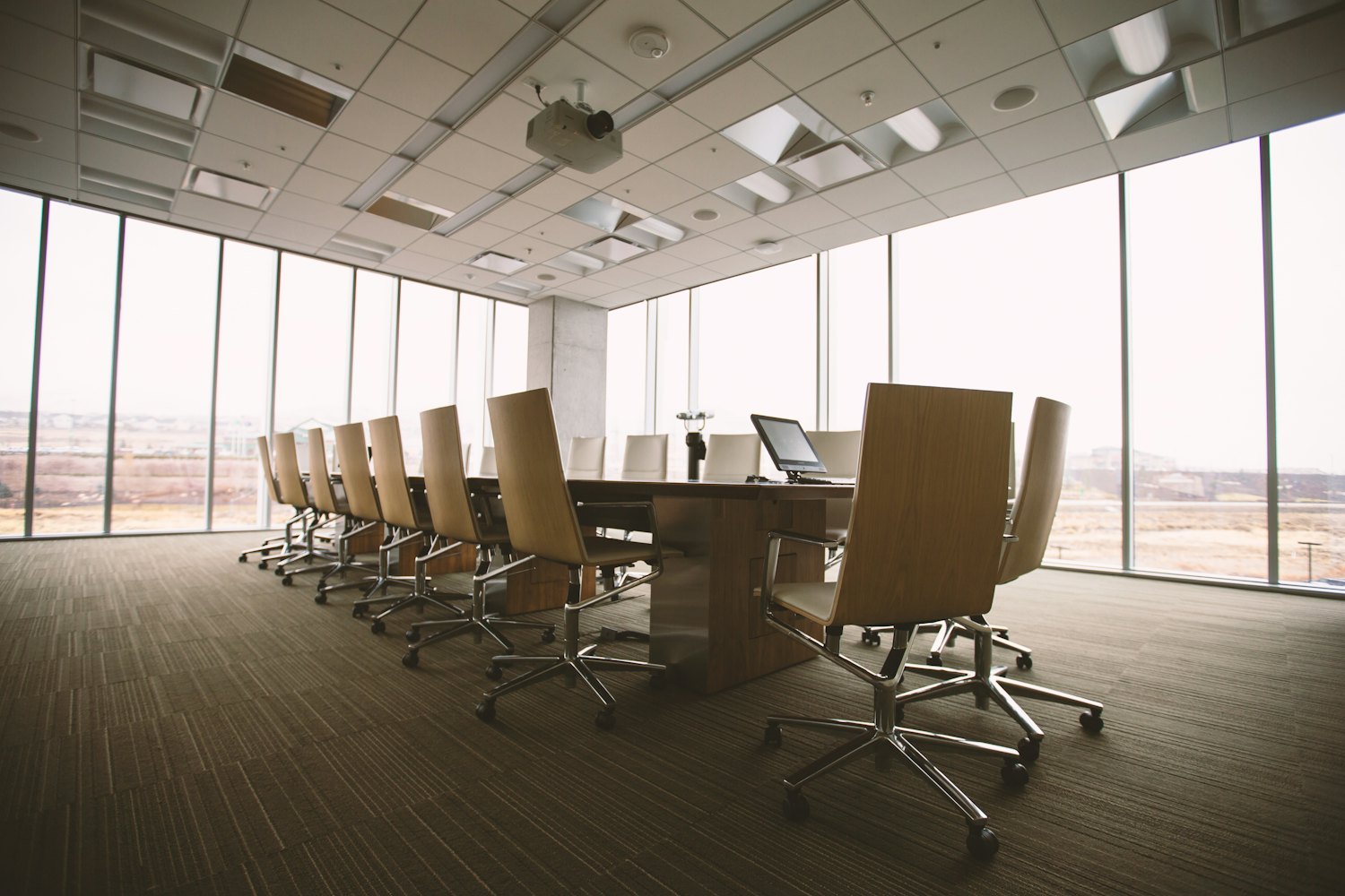 An empty boardroom with a long table and floor to ceiling windows, where steering committees meet